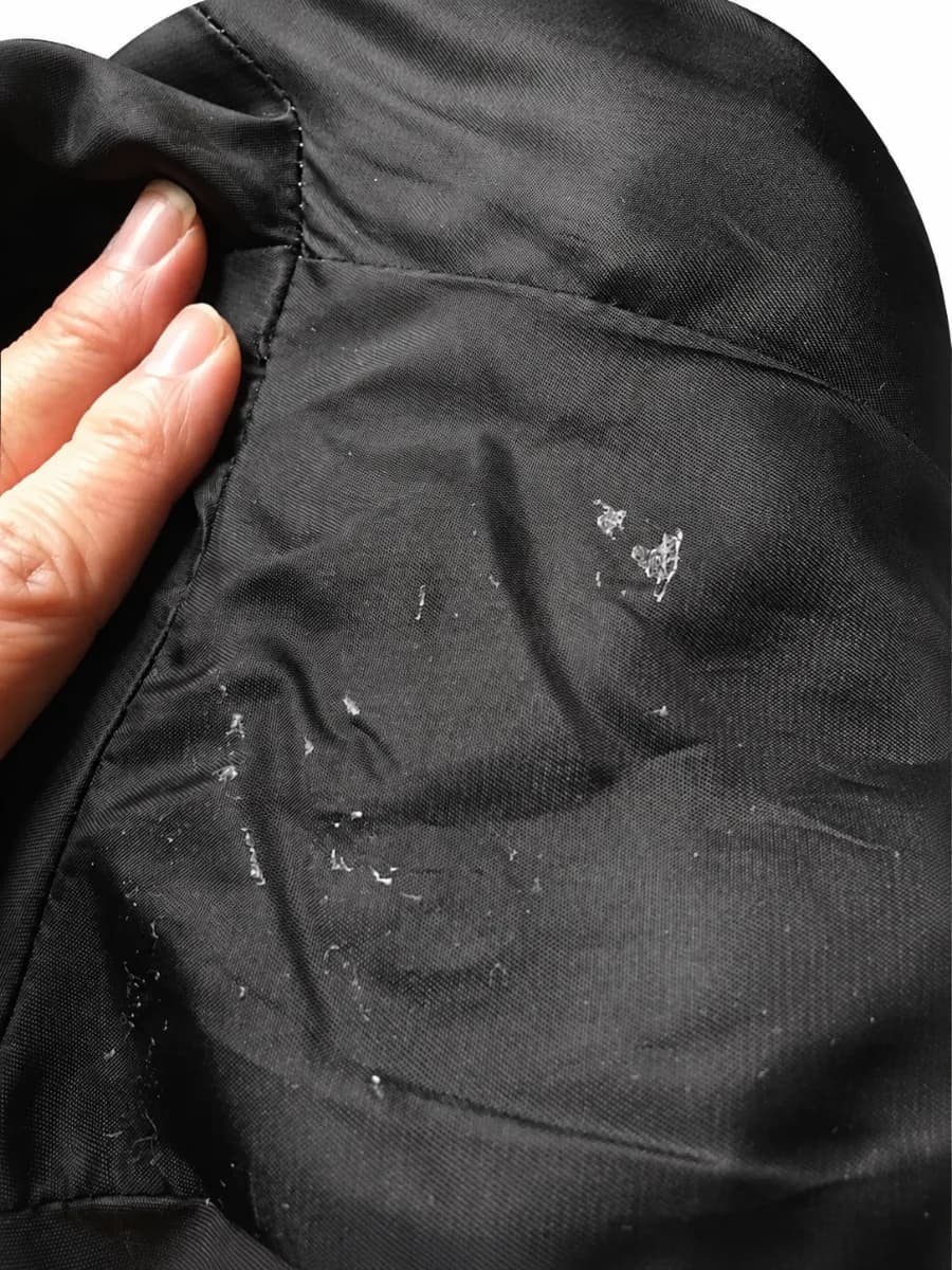 Adhesive residue remaining on dark fabric after an underarm sweat pad was removed
