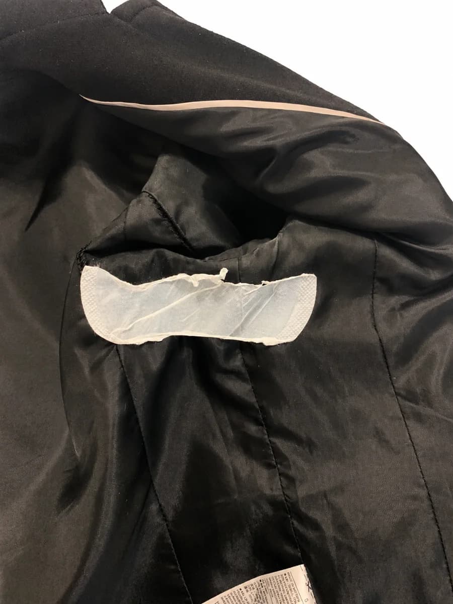 Part of an underarm sweat pad remaining attached to the inside of a dark garment during removal