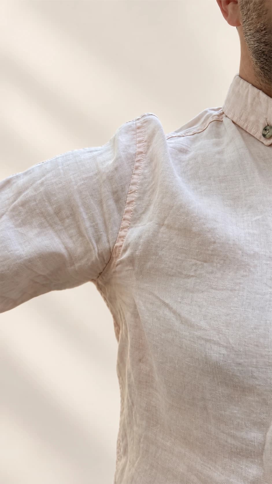 Underarm sweat pad beneath a light pink shirt with the arm raised